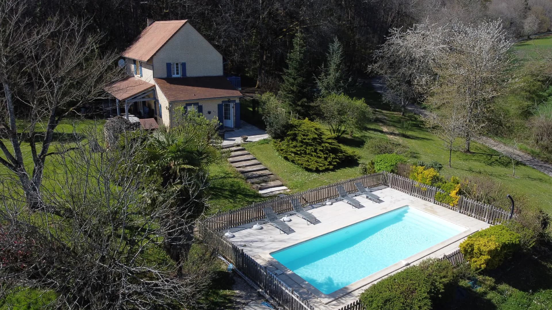 Vue aérienne de la piscine chauffée de La Bergerie de Thenon, entourée de transats